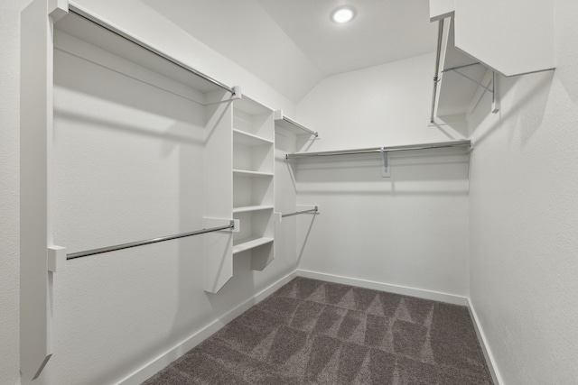 walk in closet with dark carpet and lofted ceiling