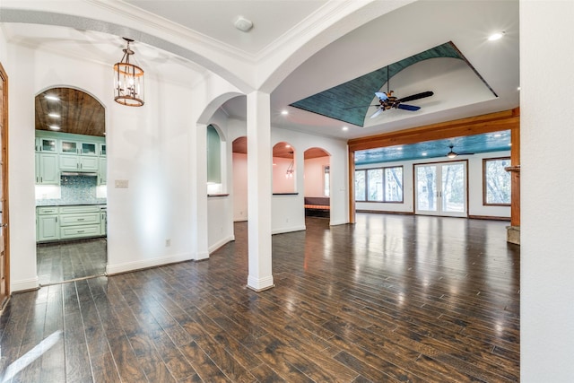 interior space with crown molding, dark hardwood / wood-style flooring, a raised ceiling, and ceiling fan with notable chandelier