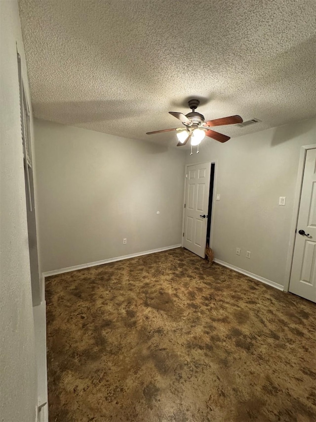 unfurnished room with ceiling fan, dark carpet, and a textured ceiling