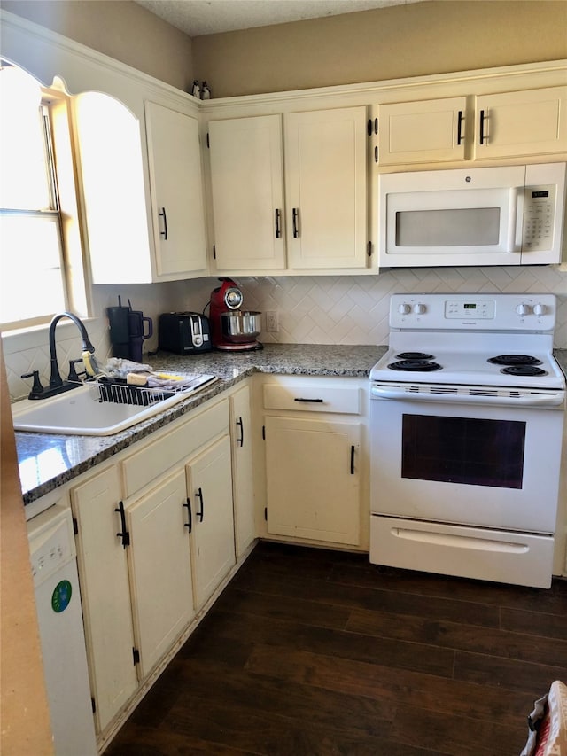 kitchen with dark hardwood / wood-style flooring, light stone countertops, sink, and white appliances