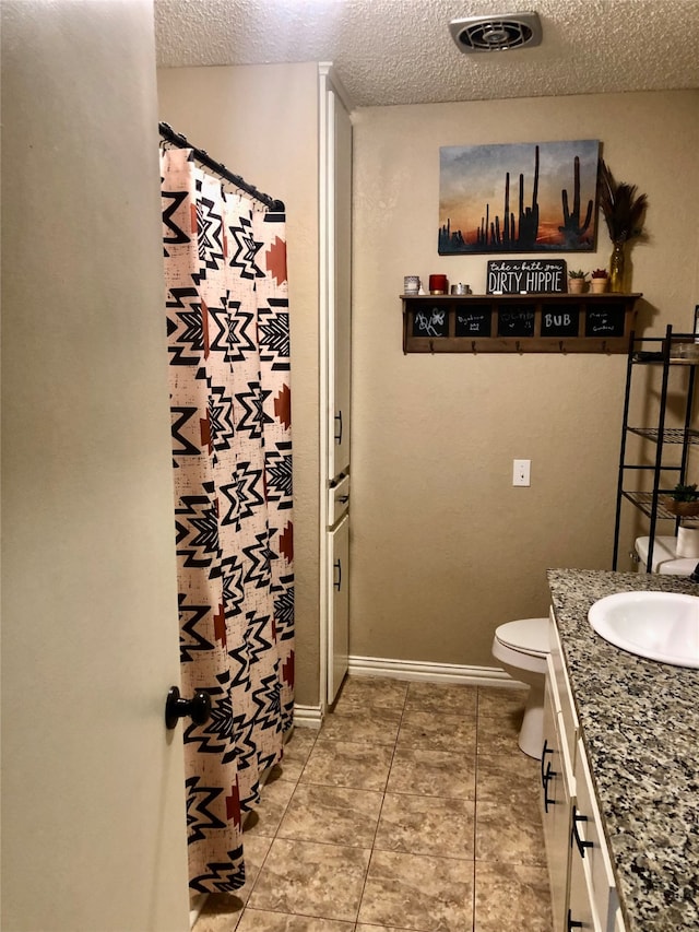 bathroom featuring vanity, a textured ceiling, toilet, and tile patterned floors