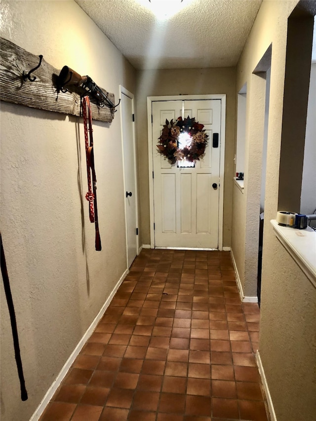 doorway to outside featuring a textured ceiling and dark tile patterned floors