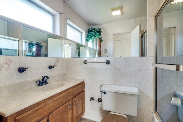 bathroom with vanity, tile walls, toilet, and walk in shower