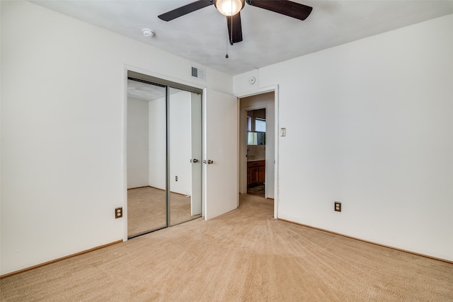 unfurnished bedroom with light carpet, a closet, and ceiling fan