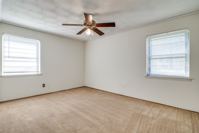 spare room featuring crown molding, light colored carpet, and ceiling fan