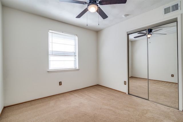 unfurnished bedroom with light carpet, a closet, and ceiling fan