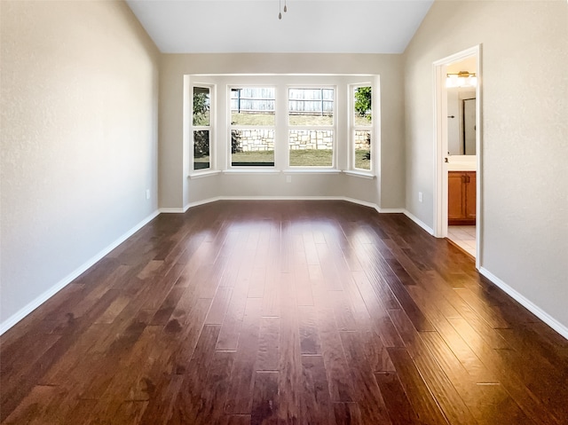 spare room featuring lofted ceiling and dark hardwood / wood-style floors