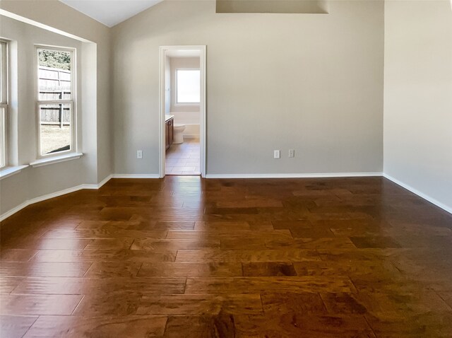 spare room featuring vaulted ceiling and dark hardwood / wood-style floors