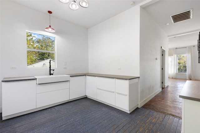 kitchen featuring white cabinetry, dark hardwood / wood-style flooring, sink, and hanging light fixtures