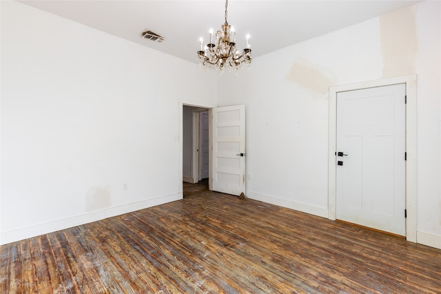 unfurnished room with a chandelier and dark hardwood / wood-style floors