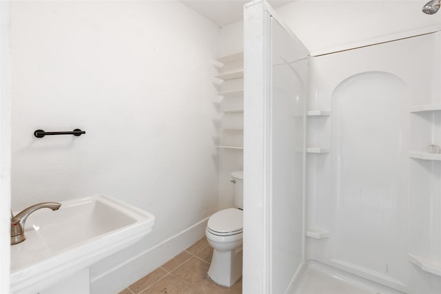 bathroom featuring toilet, walk in shower, sink, and tile patterned flooring