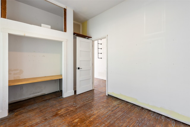 unfurnished bedroom with built in desk and dark wood-type flooring