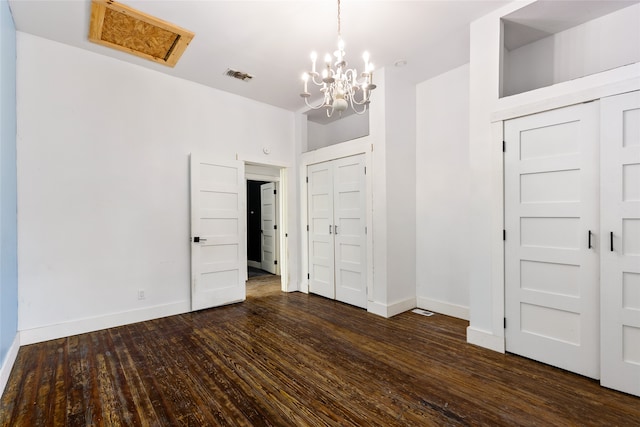 unfurnished bedroom featuring a notable chandelier, dark hardwood / wood-style floors, and a closet