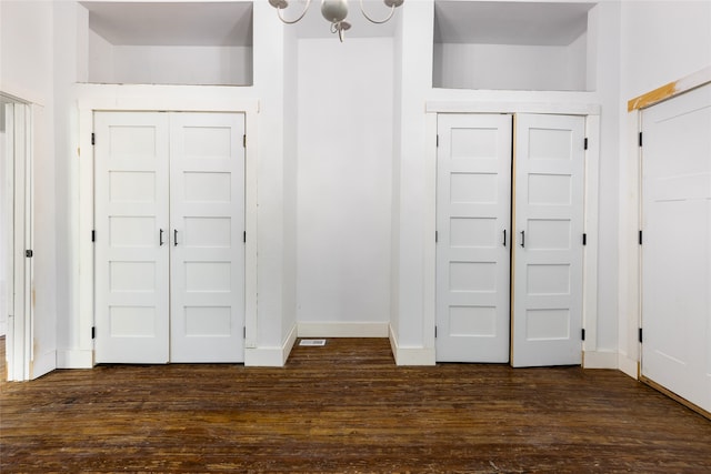 interior space with two closets, dark hardwood / wood-style floors, and an inviting chandelier