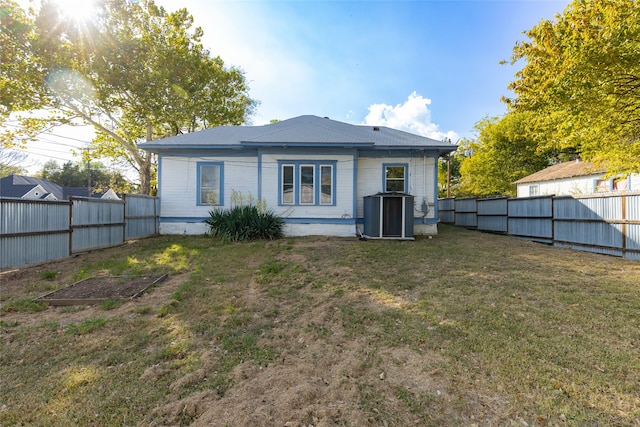 back of property with central AC and a lawn