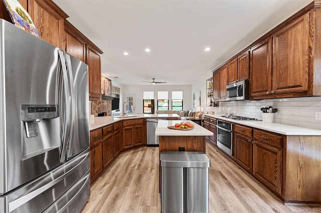 kitchen featuring sink, appliances with stainless steel finishes, a center island, tasteful backsplash, and kitchen peninsula