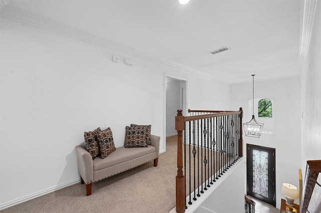 hall featuring an inviting chandelier, crown molding, and carpet