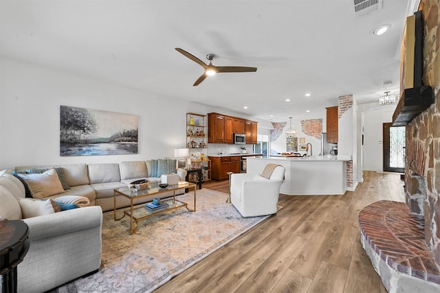 living room with ceiling fan, sink, and light wood-type flooring