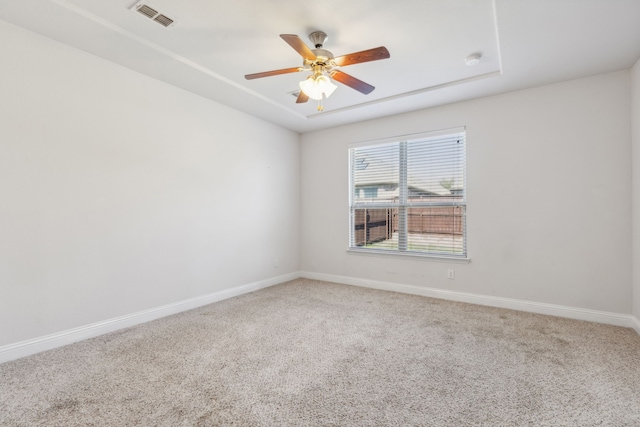 carpeted empty room with ceiling fan and a tray ceiling