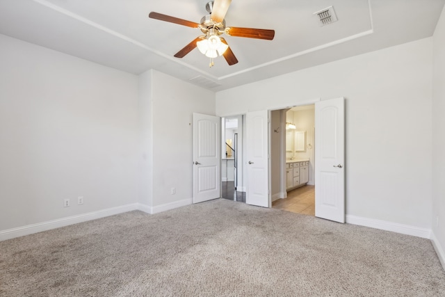 unfurnished bedroom with ceiling fan, light colored carpet, and ensuite bath