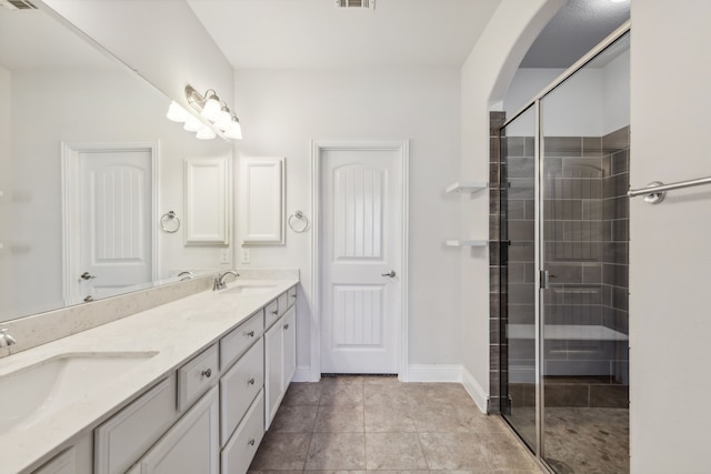 bathroom with a shower with door, vanity, and tile patterned floors