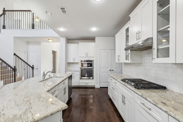 kitchen with white cabinetry, appliances with stainless steel finishes, light stone countertops, and sink