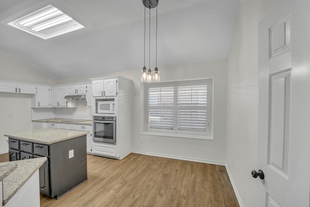 kitchen featuring white cabinetry, a center island, hanging light fixtures, oven, and white microwave