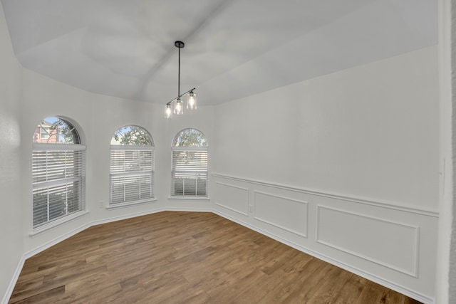 unfurnished dining area featuring a chandelier and wood-type flooring