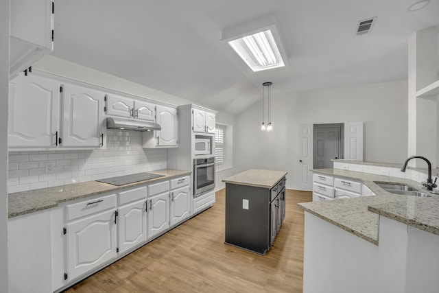 kitchen with white cabinets, oven, a kitchen island, and sink