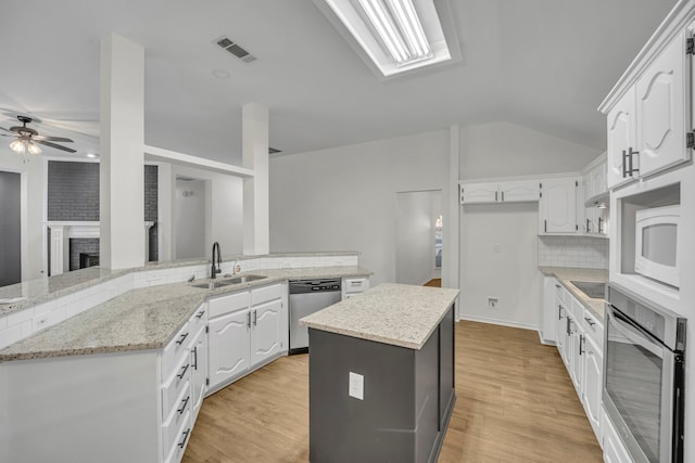 kitchen featuring kitchen peninsula, light stone countertops, white cabinets, and appliances with stainless steel finishes