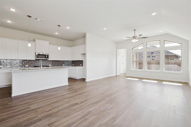 kitchen with hardwood / wood-style flooring, decorative light fixtures, a center island with sink, white cabinets, and ceiling fan