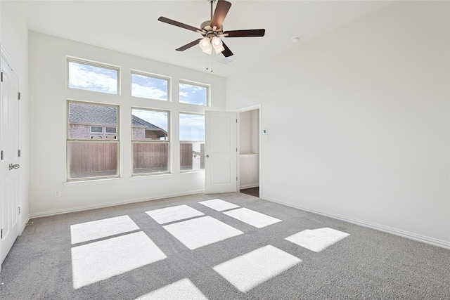 carpeted empty room featuring a towering ceiling and ceiling fan