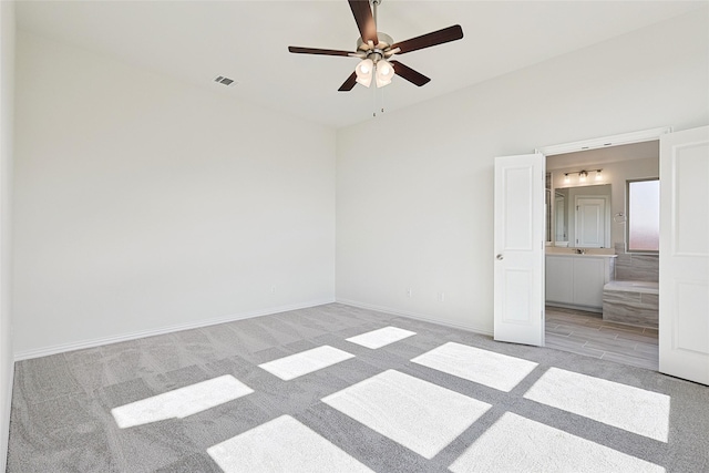 unfurnished bedroom with ensuite bath, ceiling fan, and light colored carpet