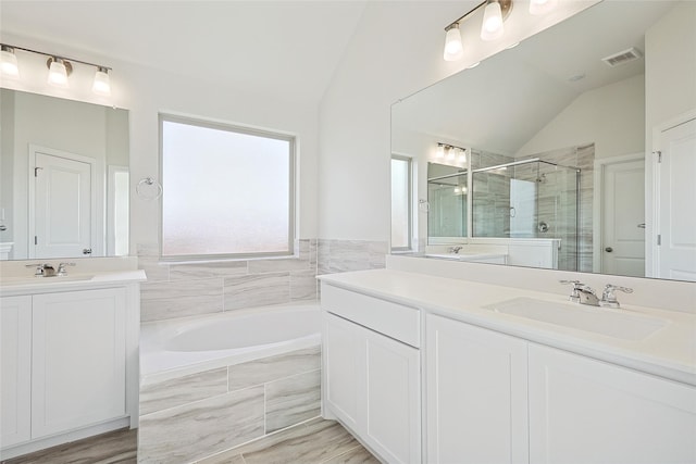 bathroom with independent shower and bath, lofted ceiling, and vanity