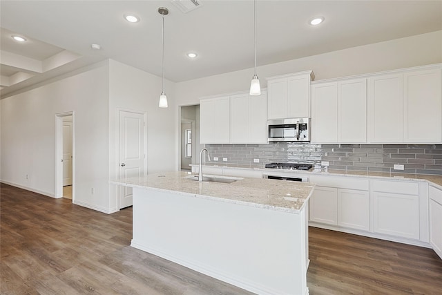 kitchen featuring decorative light fixtures, a center island with sink, white cabinets, appliances with stainless steel finishes, and sink