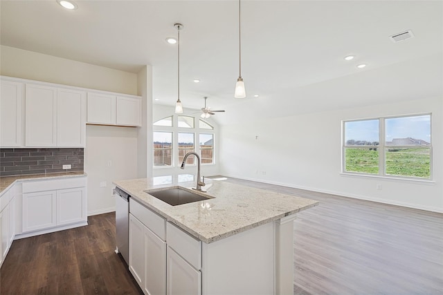 kitchen with light stone counters, dishwasher, a center island with sink, white cabinetry, and sink