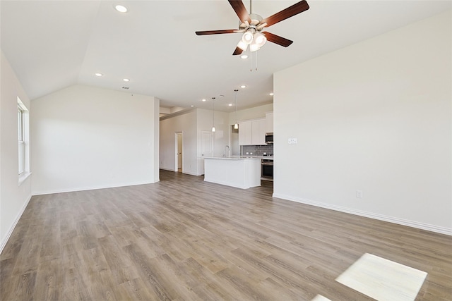 unfurnished living room featuring lofted ceiling, light wood-type flooring, ceiling fan, and sink