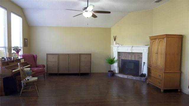 living area featuring lofted ceiling, dark wood-style flooring, a fireplace, and ceiling fan