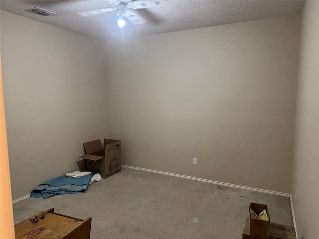 carpeted spare room with baseboards, ceiling fan, visible vents, and a textured ceiling