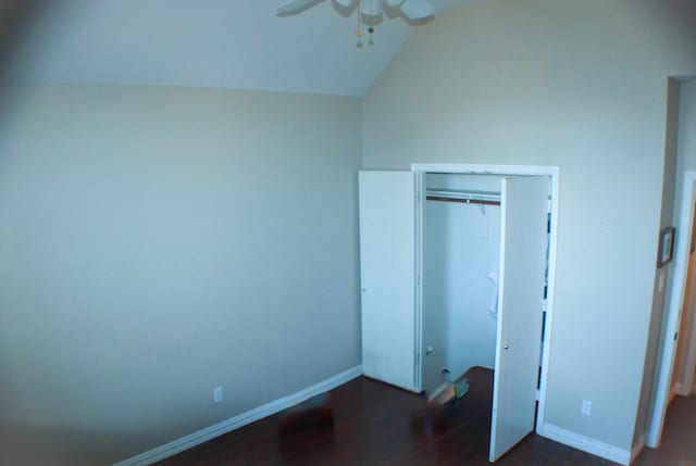 unfurnished bedroom featuring lofted ceiling, dark wood-style flooring, ceiling fan, and baseboards