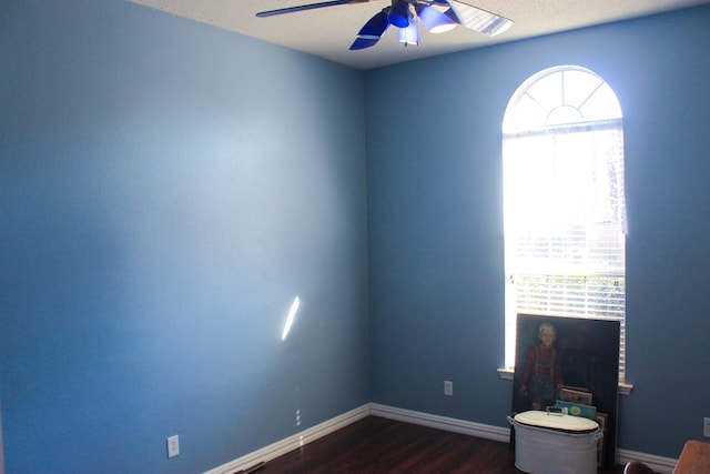 interior space featuring dark wood-style flooring, ceiling fan, and baseboards