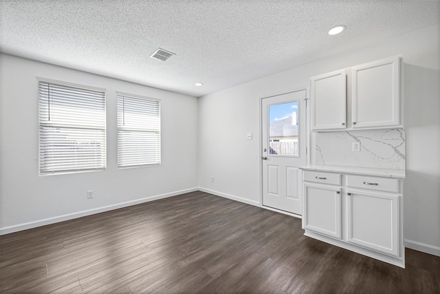 unfurnished dining area with a textured ceiling and dark hardwood / wood-style floors