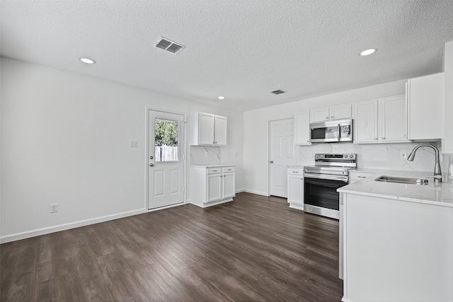 kitchen featuring sink, a textured ceiling, stainless steel appliances, white cabinets, and dark wood-type flooring