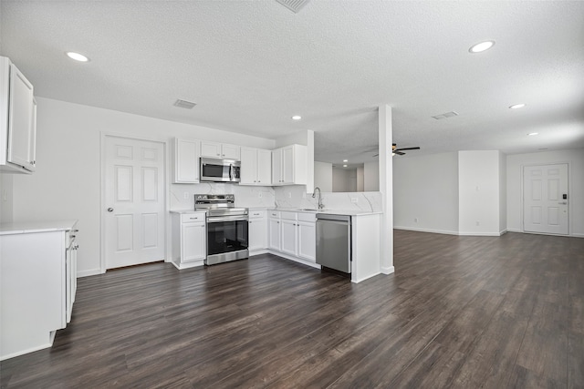 kitchen featuring sink, white cabinetry, appliances with stainless steel finishes, a textured ceiling, and dark hardwood / wood-style flooring