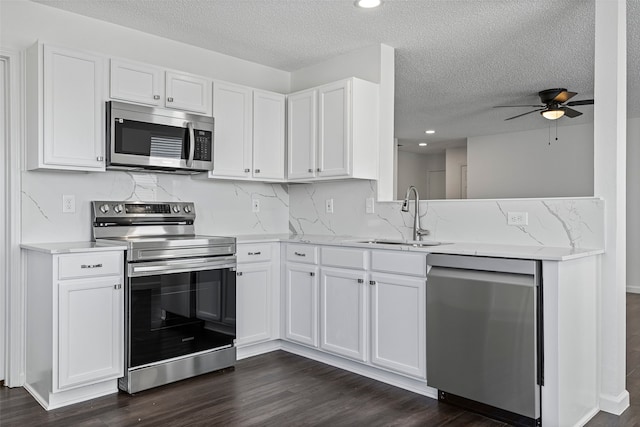 kitchen with dark hardwood / wood-style floors, stainless steel appliances, sink, white cabinetry, and light stone counters