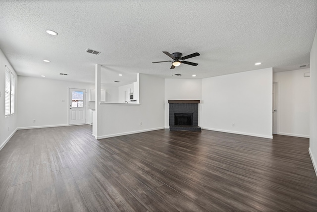 unfurnished living room with a fireplace, a textured ceiling, and dark hardwood / wood-style flooring