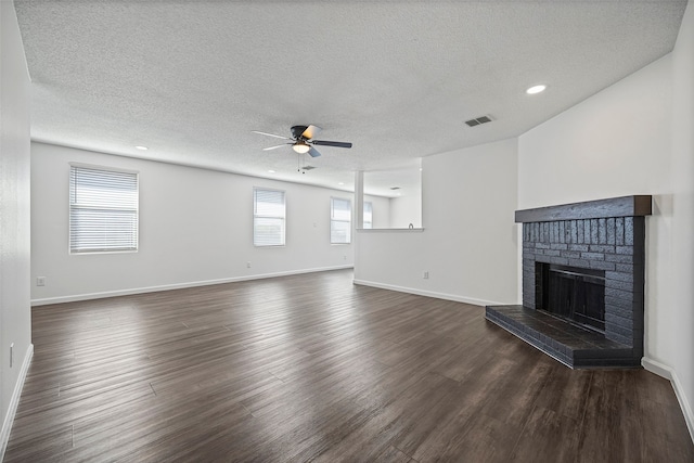 unfurnished living room featuring dark wood-type flooring, ceiling fan, a textured ceiling, and a fireplace