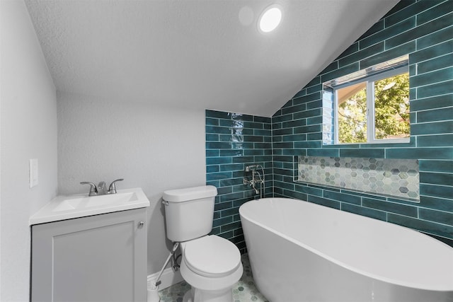 bathroom featuring lofted ceiling, a tub to relax in, toilet, vanity, and a textured ceiling