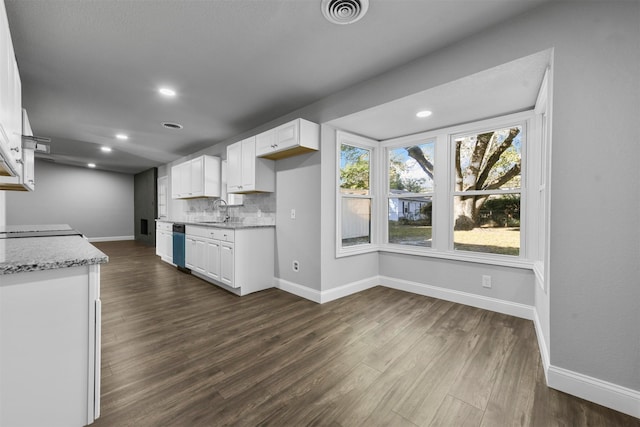 kitchen with light stone countertops, sink, dark hardwood / wood-style flooring, stainless steel dishwasher, and white cabinets