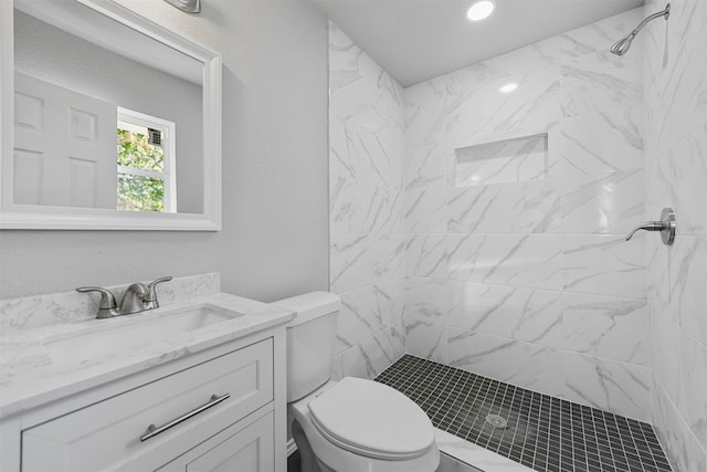 bathroom featuring toilet, vanity, and a tile shower